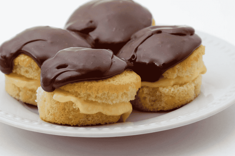 A plate featuring three Boston Cream Pies, each adorned with rich chocolate frosting