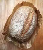 A loaf of bread resting on a rustic wooden table, showcasing its golden crust and inviting texture